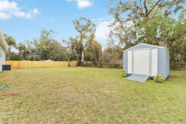 view of yard featuring an outbuilding, a fenced backyard, central AC unit, and a storage unit