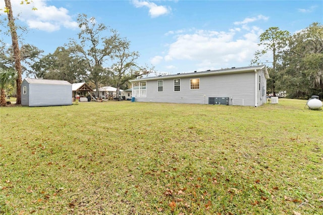 rear view of house featuring a yard, a shed, an outdoor structure, and central air condition unit