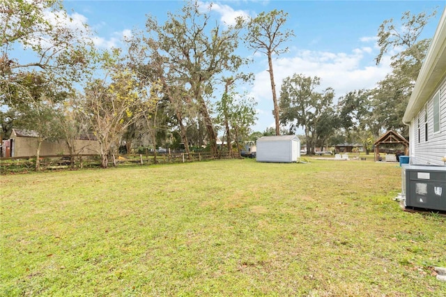 view of yard with fence, a storage unit, and an outbuilding