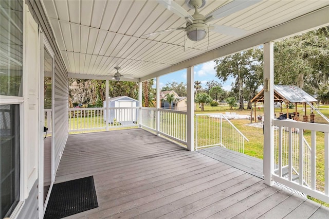deck featuring a yard, an outdoor structure, a ceiling fan, and a shed