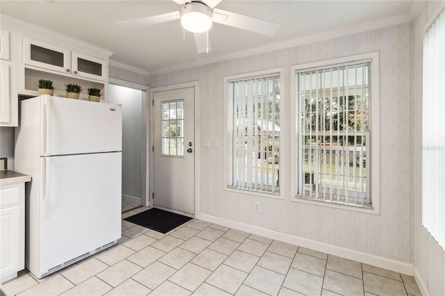 kitchen featuring freestanding refrigerator, crown molding, ceiling fan, white cabinets, and baseboards