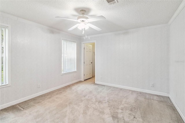 carpeted spare room with ceiling fan, a healthy amount of sunlight, and crown molding