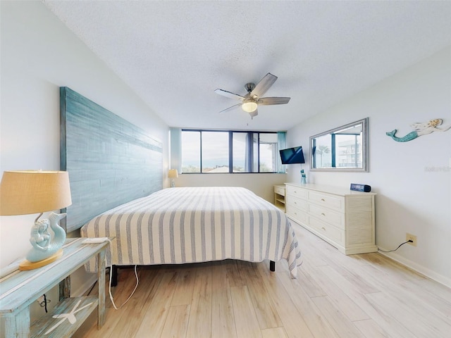 bedroom with ceiling fan, a textured ceiling, and light hardwood / wood-style flooring