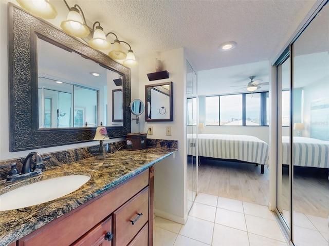 bathroom with ceiling fan, a textured ceiling, tile patterned floors, and vanity