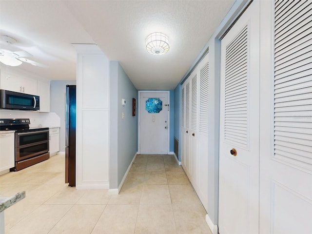 corridor featuring light tile patterned flooring and a textured ceiling