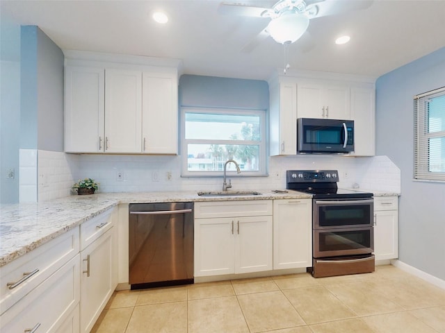 kitchen with sink, light stone counters, light tile patterned floors, appliances with stainless steel finishes, and white cabinets