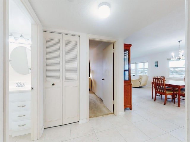 hall featuring light tile patterned flooring and a chandelier