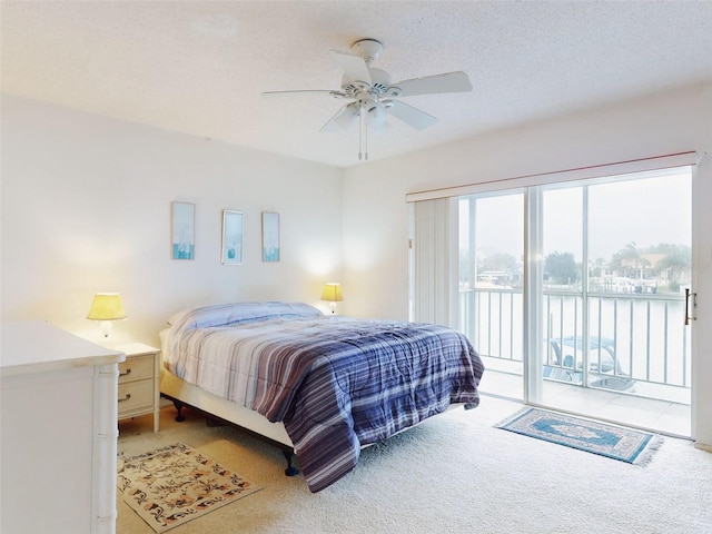 carpeted bedroom featuring ceiling fan, access to exterior, and a textured ceiling