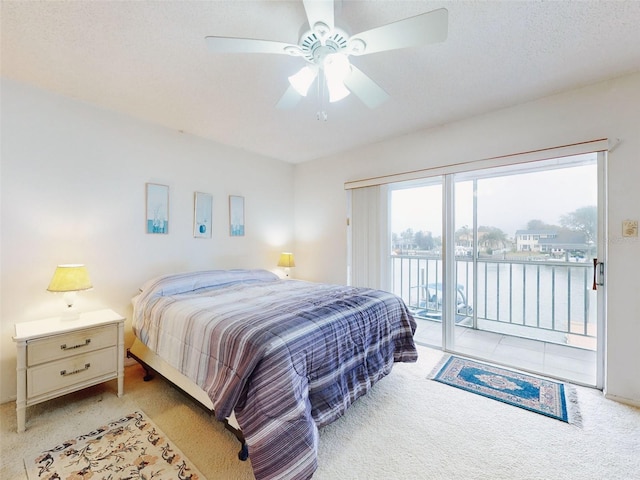 bedroom with a textured ceiling, access to outside, light colored carpet, and ceiling fan