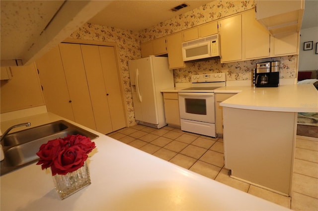 kitchen with sink, light tile patterned floors, kitchen peninsula, white appliances, and cream cabinetry