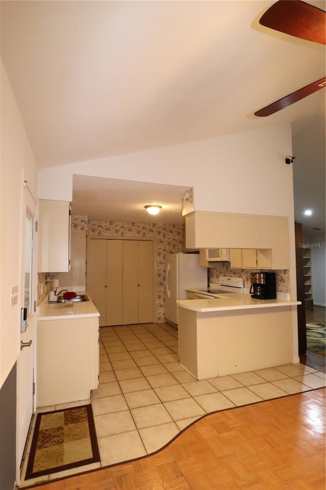 kitchen with lofted ceiling, sink, kitchen peninsula, light parquet flooring, and white appliances