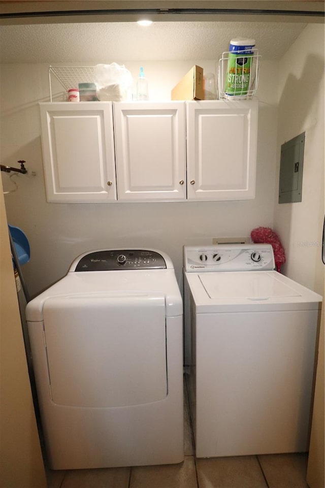 laundry area with light tile patterned floors, washer and clothes dryer, electric panel, and cabinets