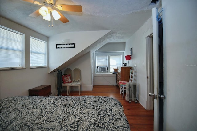 bedroom with cooling unit, dark hardwood / wood-style flooring, radiator, and multiple windows