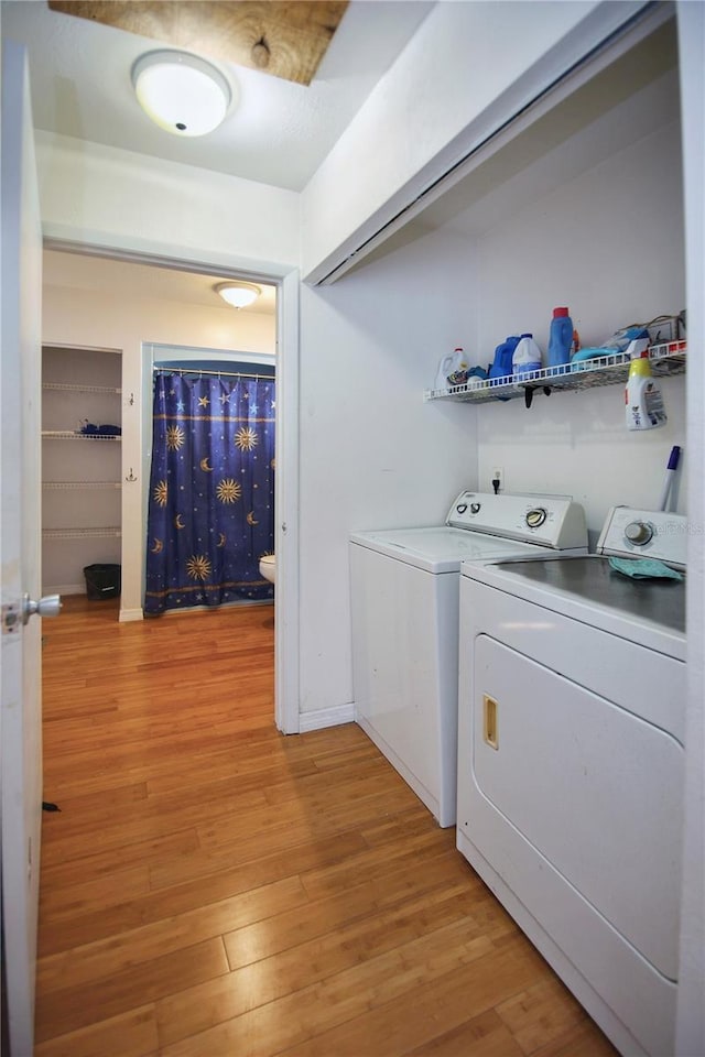 clothes washing area with light hardwood / wood-style flooring and washer and clothes dryer