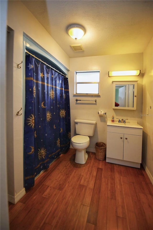 bathroom featuring wood-type flooring, vanity, toilet, a textured ceiling, and a shower with shower curtain