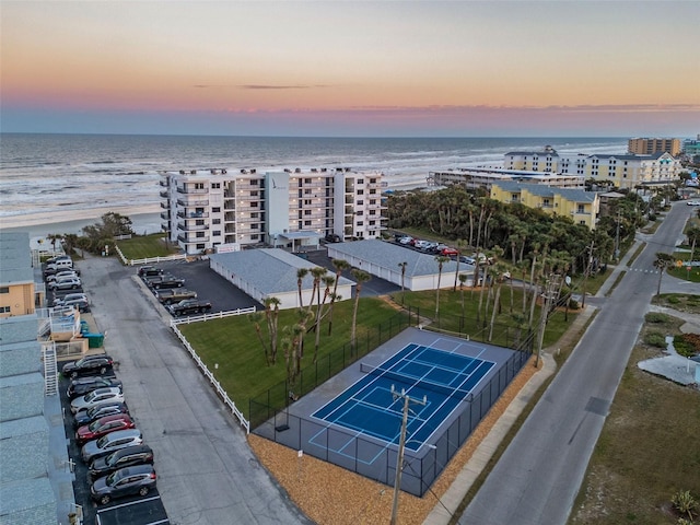 aerial view at dusk featuring a water view and a view of the beach