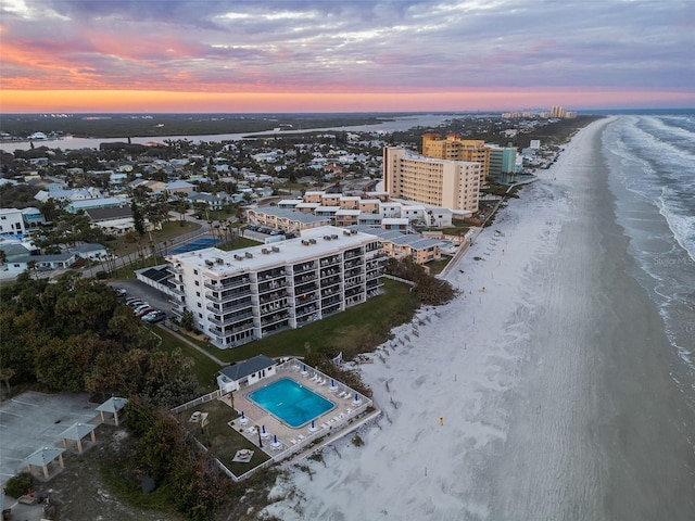 aerial view at dusk with a beach view and a water view