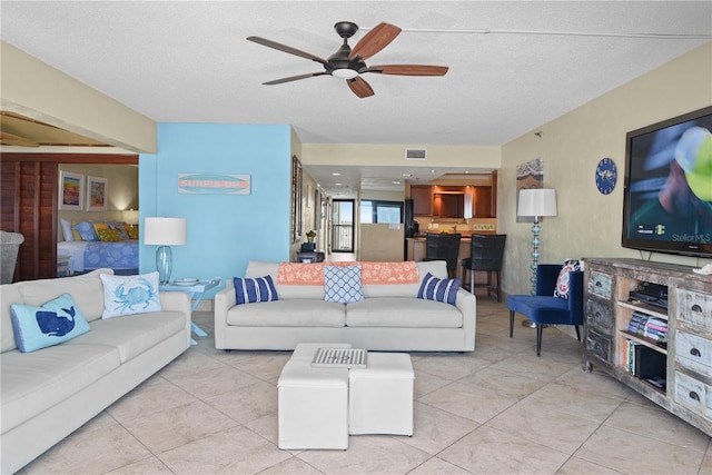 living room featuring ceiling fan, light tile patterned floors, and a textured ceiling