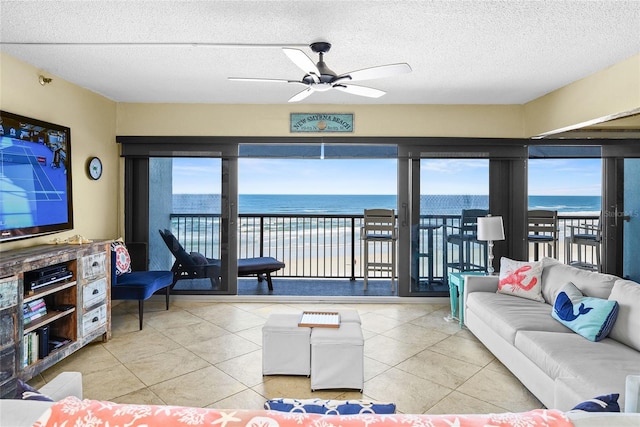 tiled living room with a water view, ceiling fan, and a textured ceiling