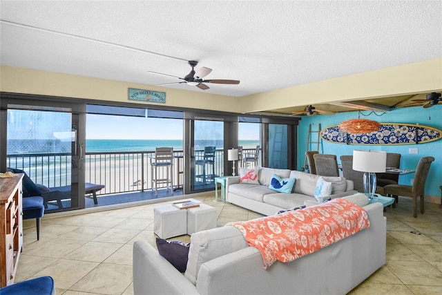 living room with a water view, light tile patterned floors, a textured ceiling, and ceiling fan