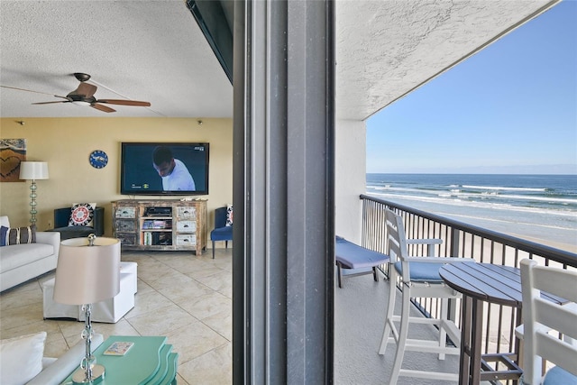 balcony featuring ceiling fan, a beach view, and a water view