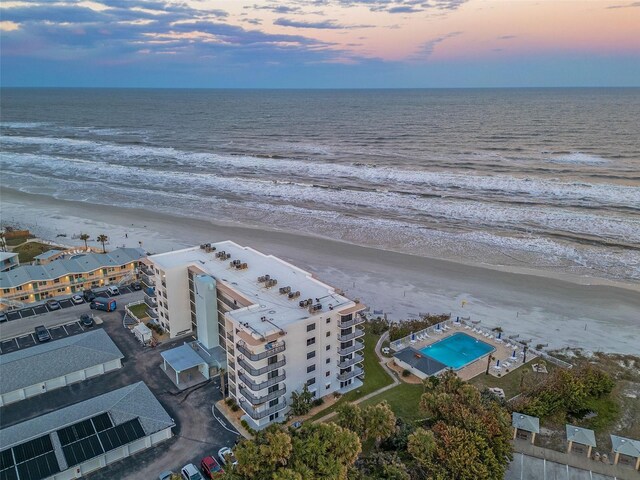 aerial view at dusk with a view of the beach and a water view