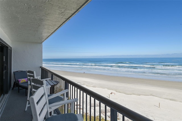 balcony featuring a water view and a view of the beach