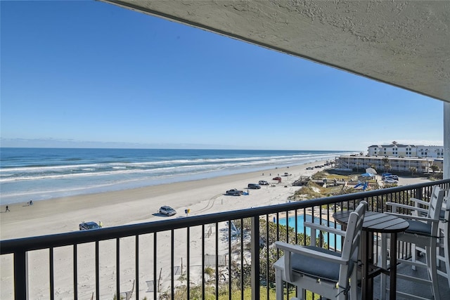 balcony featuring a view of the beach and a water view