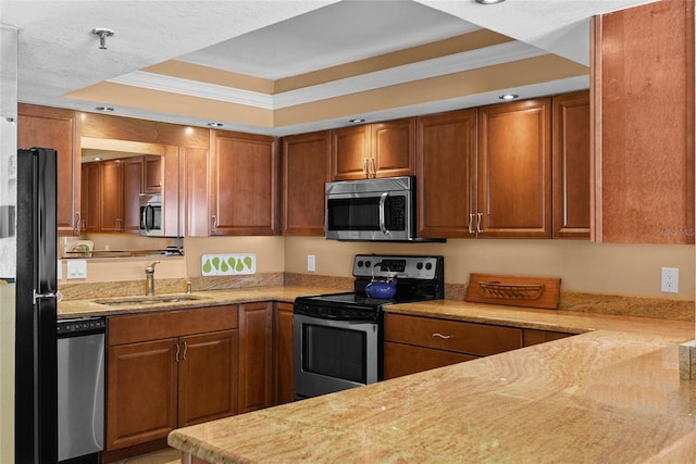 kitchen with light stone counters, sink, a tray ceiling, and appliances with stainless steel finishes