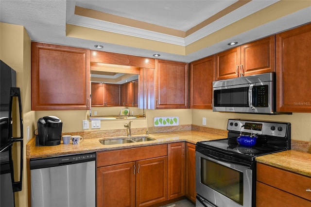 kitchen featuring light stone counters, stainless steel appliances, a raised ceiling, and sink