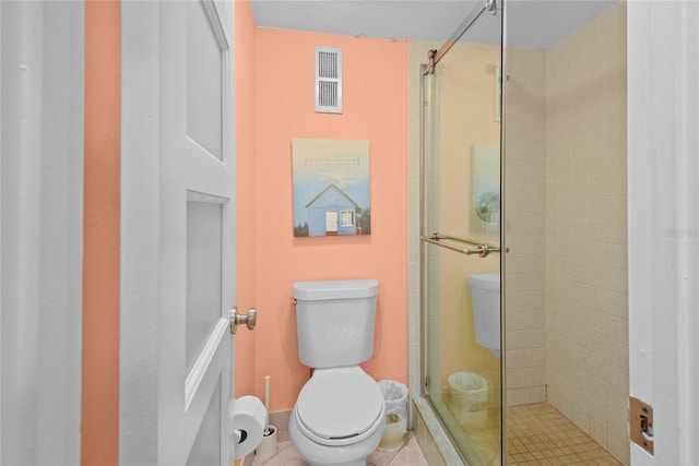 bathroom featuring a shower with door, tile patterned flooring, and toilet