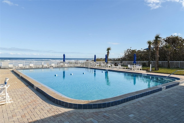 view of pool featuring a water view and a patio