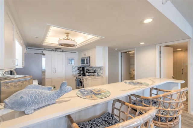 kitchen featuring a breakfast bar area, white cabinetry, tasteful backsplash, light hardwood / wood-style flooring, and stainless steel appliances