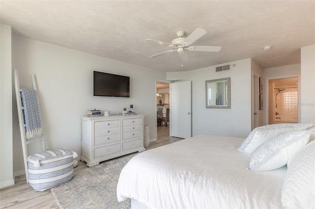 bedroom featuring connected bathroom, ceiling fan, and light wood-type flooring