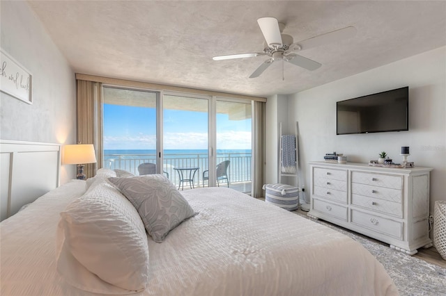 bedroom with ceiling fan, access to exterior, and a wall of windows