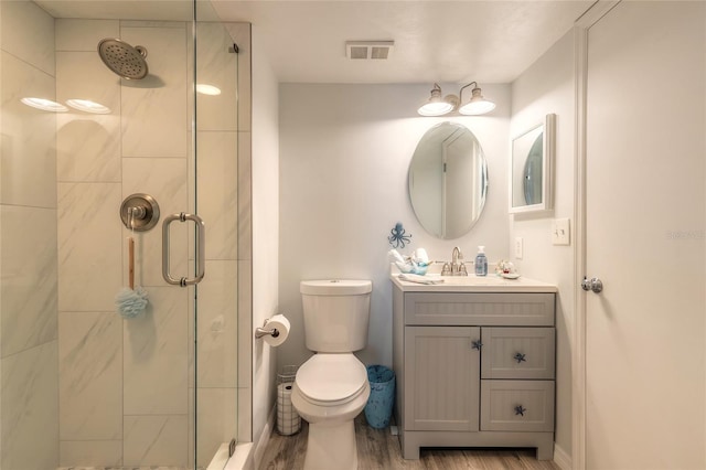 bathroom featuring vanity, toilet, a shower with shower door, and hardwood / wood-style floors