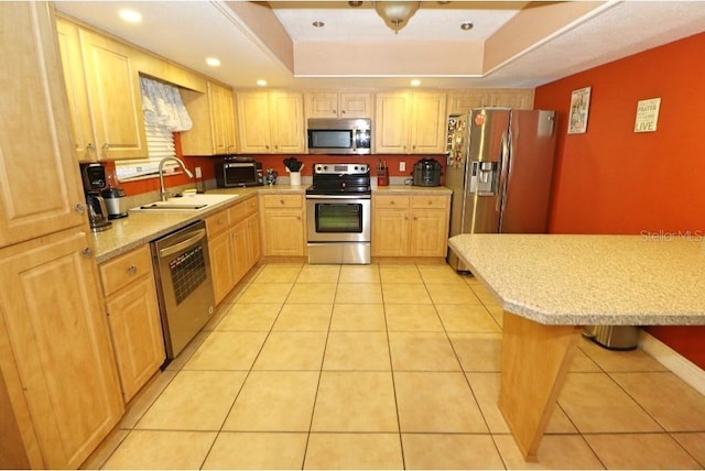 kitchen featuring light brown cabinetry, a breakfast bar, sink, light tile patterned floors, and appliances with stainless steel finishes