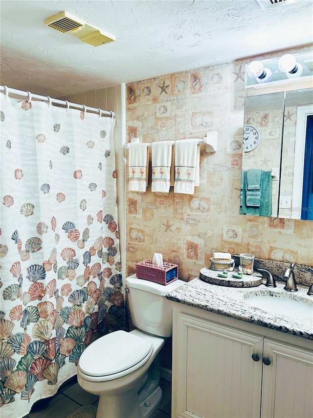 bathroom with vanity, toilet, and a textured ceiling