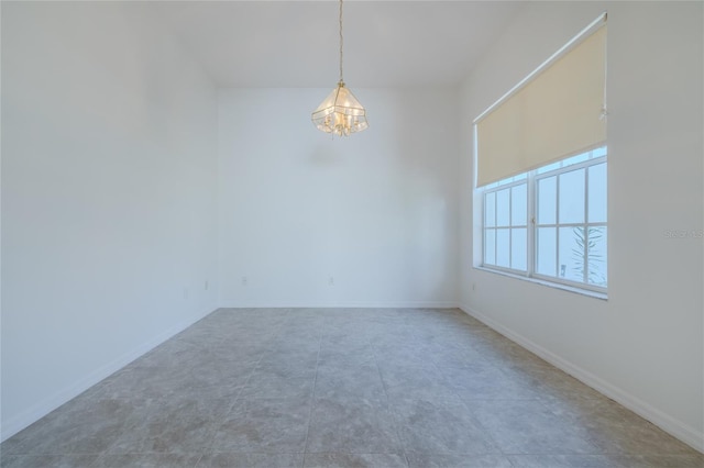 empty room with baseboards and an inviting chandelier