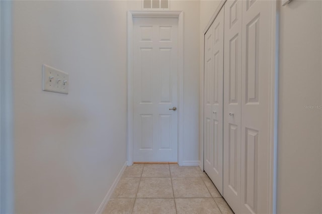 hallway featuring light tile patterned floors, visible vents, and baseboards