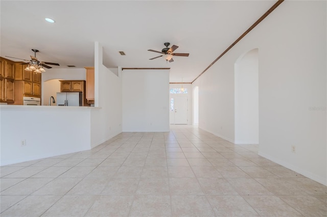 unfurnished living room with arched walkways, visible vents, ceiling fan, and light tile patterned floors