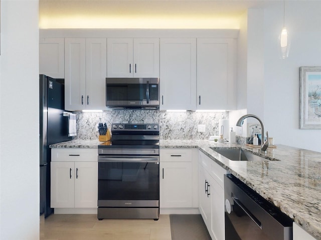 kitchen featuring pendant lighting, sink, stainless steel appliances, light stone counters, and white cabinets