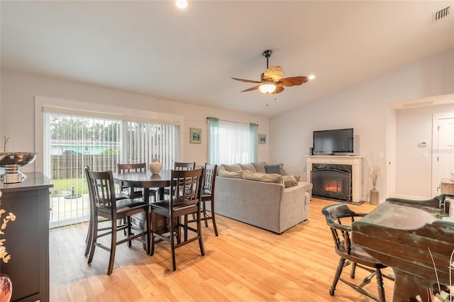 dining room with lofted ceiling, a high end fireplace, plenty of natural light, and light hardwood / wood-style floors