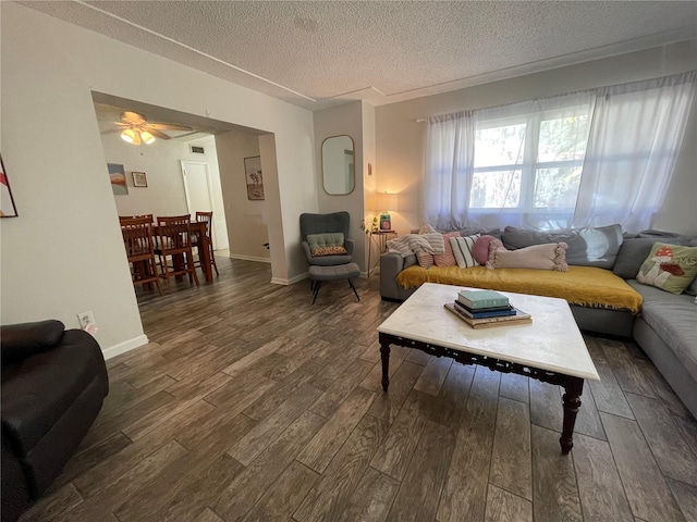 living room with ceiling fan, a textured ceiling, and dark hardwood / wood-style flooring