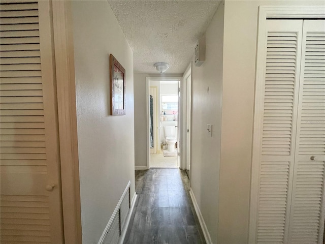 corridor with dark hardwood / wood-style flooring and a textured ceiling