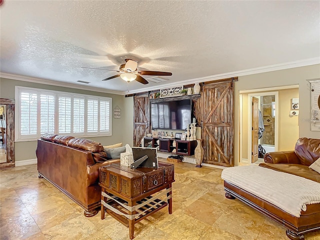 living room featuring ceiling fan, ornamental molding, and a barn door