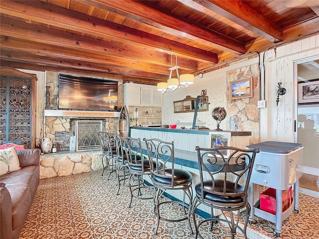 interior space with a stone fireplace, an inviting chandelier, decorative light fixtures, wooden ceiling, and beam ceiling