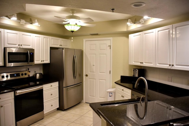 kitchen with white cabinetry, dark stone countertops, light tile patterned floors, appliances with stainless steel finishes, and ceiling fan