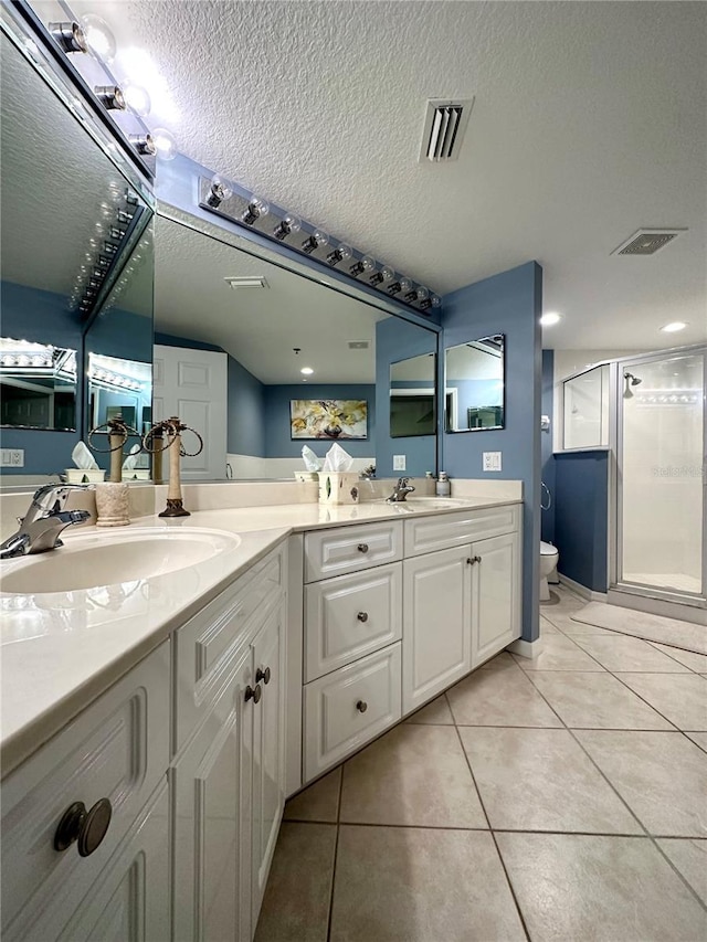 bathroom with toilet, a shower with shower door, tile patterned flooring, and a textured ceiling