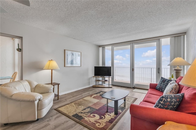 living room with light hardwood / wood-style flooring, floor to ceiling windows, and a textured ceiling